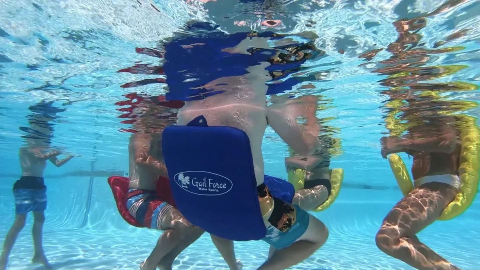 Children engaged in underwater fun, using colorful inflatable chairs in a pool. The image highlights vibrant activities in a water sports setting.